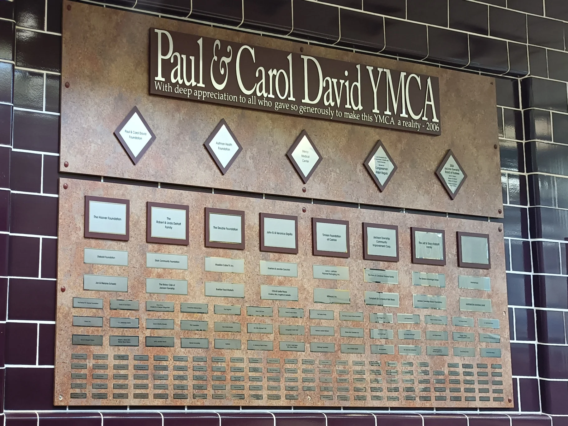 Custom donor recognition wall display with tiered nameplates and sponsor panels