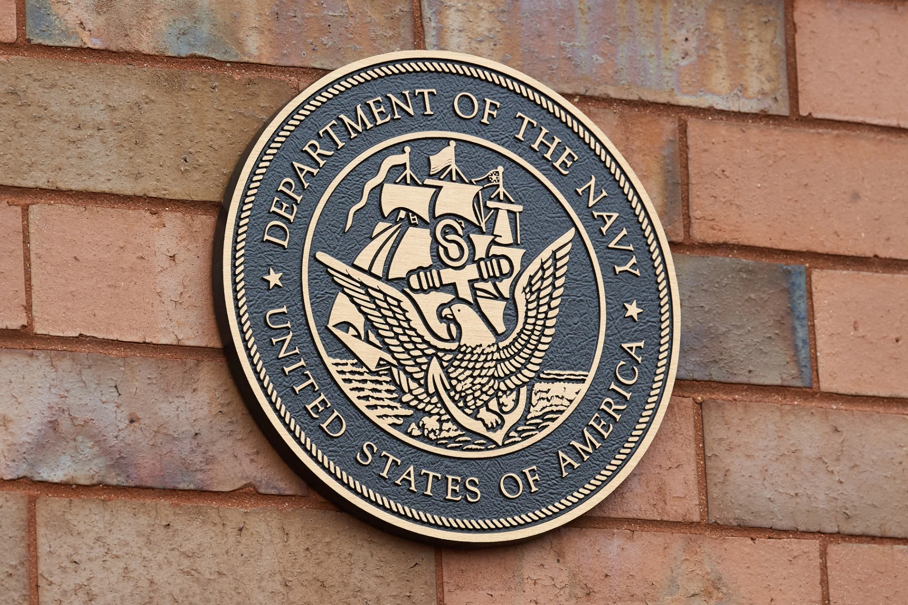 Cast bronze Department of the Navy seal mounted on a brick wall