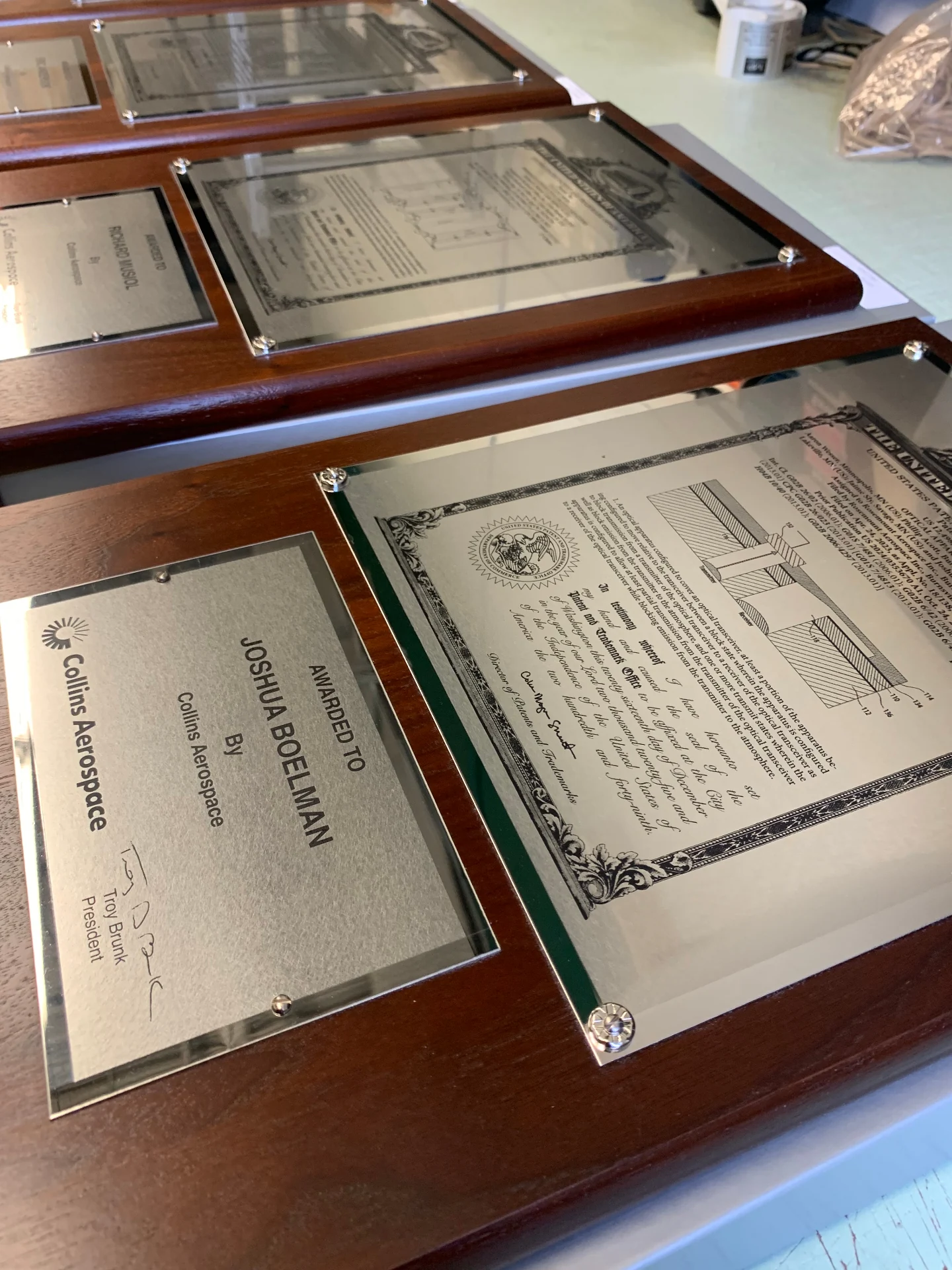 Close-up of Massillon Plaque's Art in Stainless Steel plaques featuring photo-engraved patent documents on stainless steel mounted on mahogany
